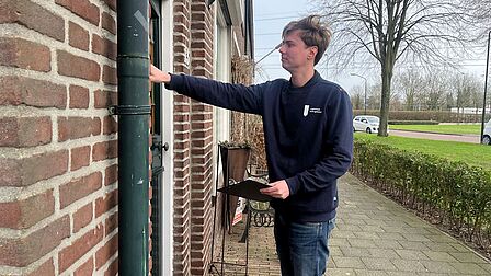 Een man belt aan bij een huis.