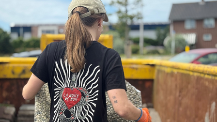 Een vrouw plaatst een tegel in de container bij het inlevermoment.